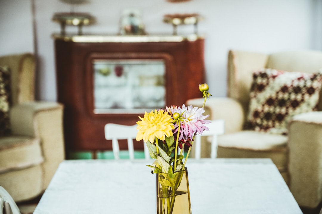 yellow and white flower on clear glass vase on white table