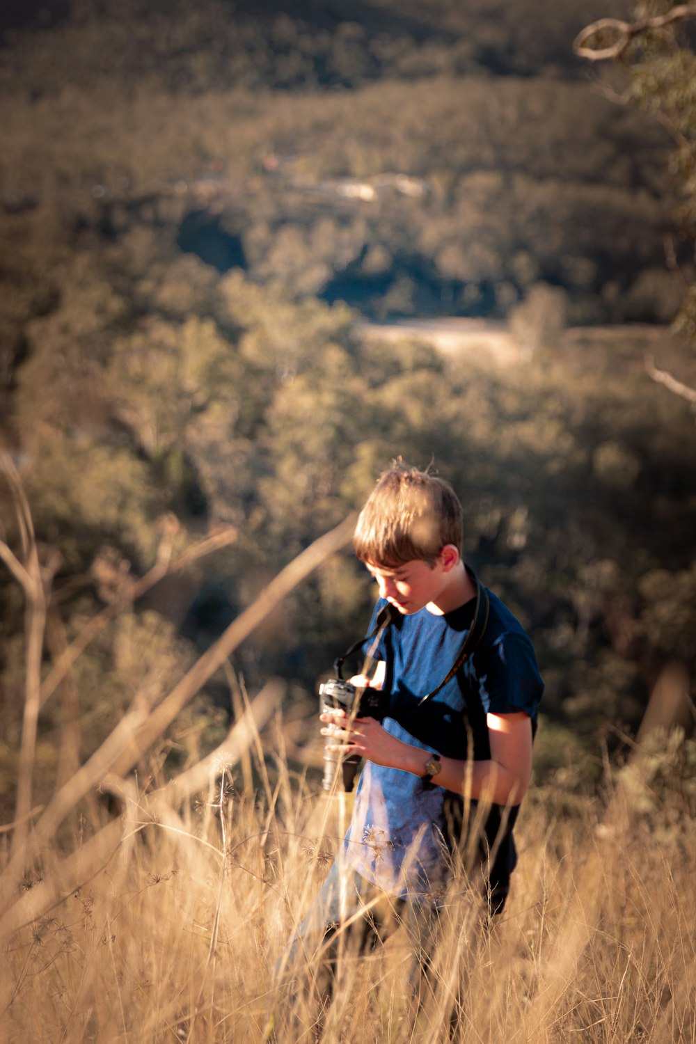 boy in blue and black polo shirt standing on brown grass field during daytime