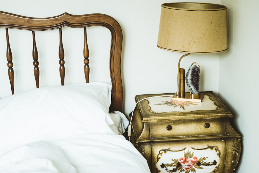 brown wooden bed frame with white table lamp