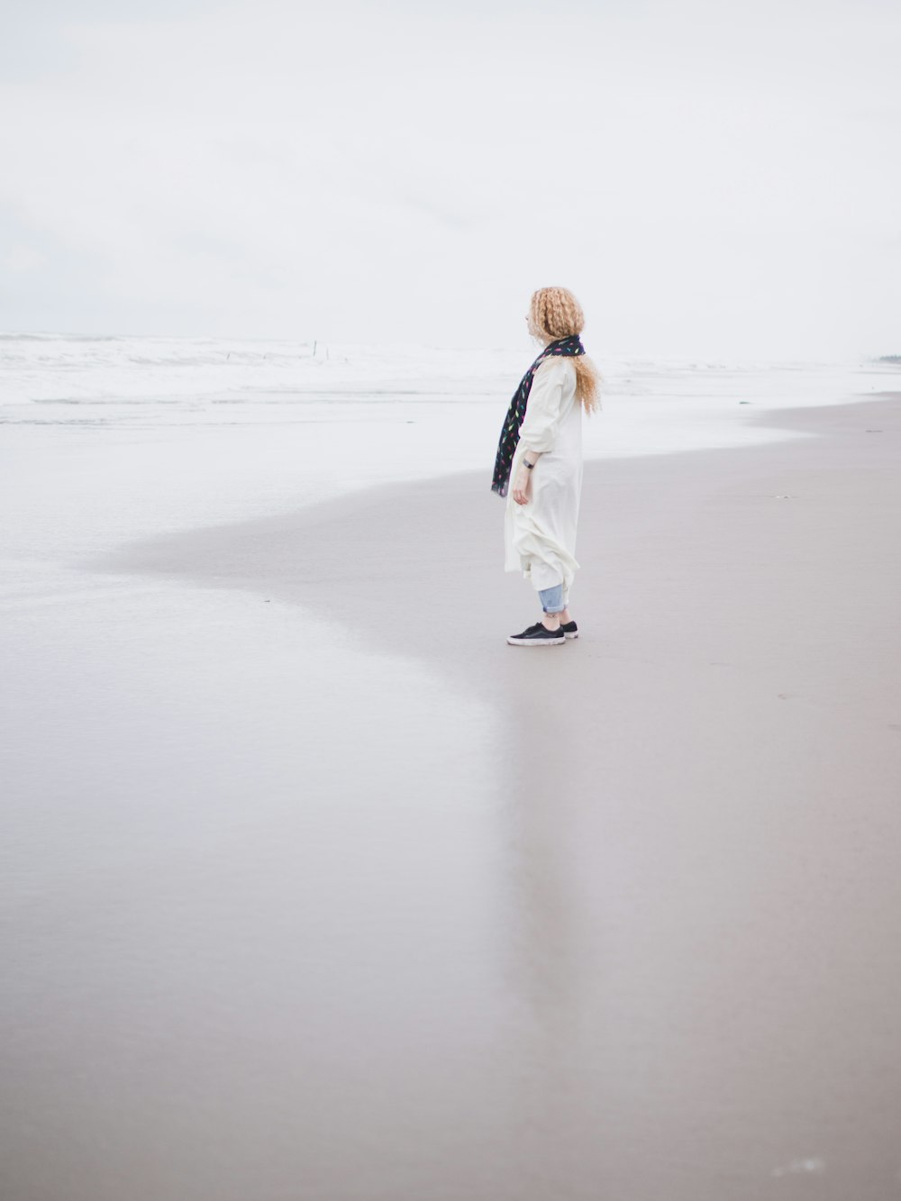Mujer con bata blanca caminando sobre arena blanca durante el día