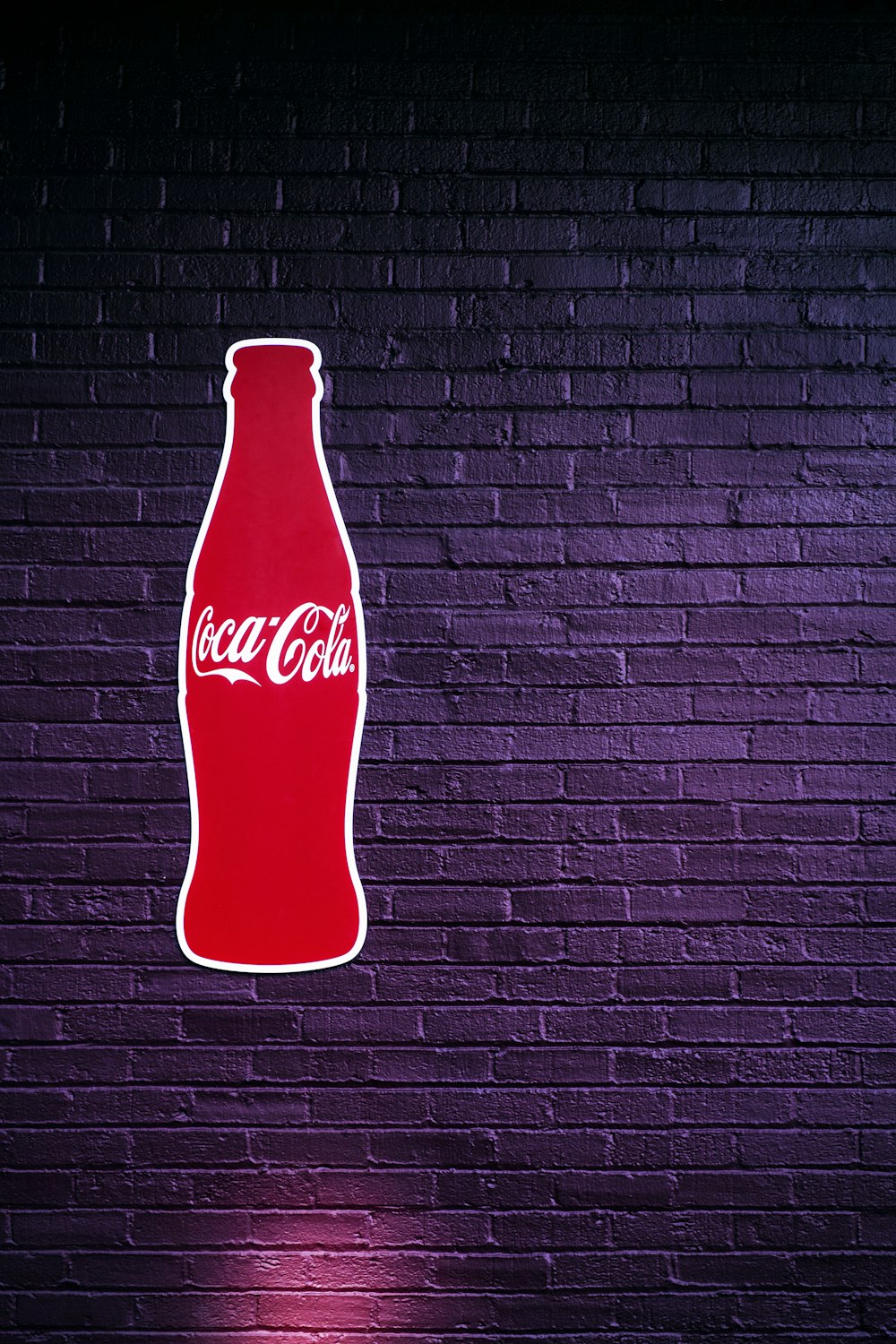 garrafa de coca-cola vermelha na parede listrada preta e branca