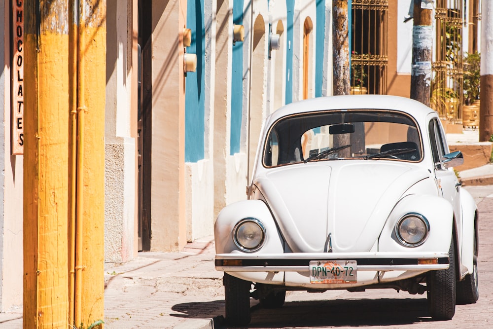 Volkswagen Beetle blanche garée à côté du bâtiment pendant la journée