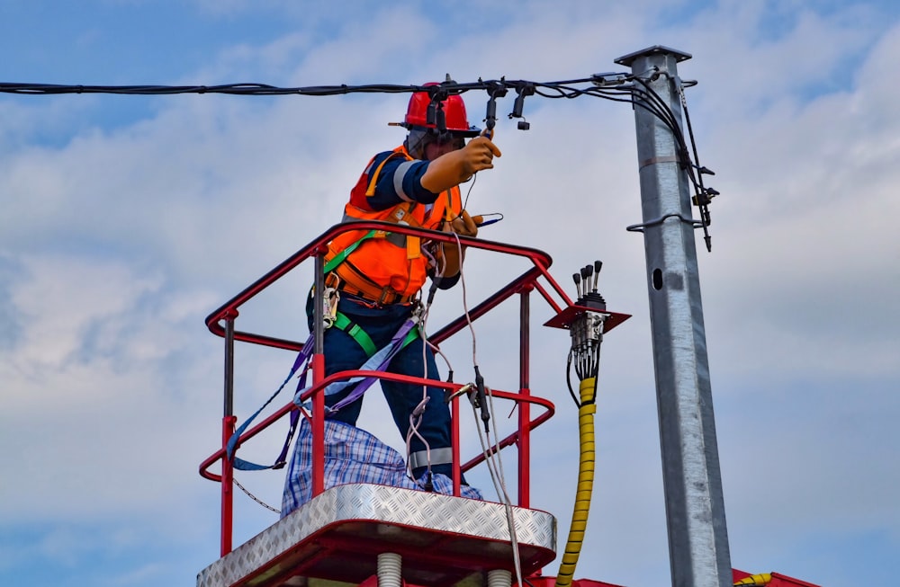 2 hommes en casque de sécurité orange circulant sur un téléphérique rouge et jaune pendant la journée