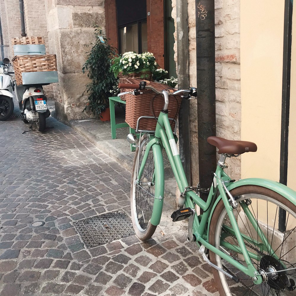 green city bike parked beside brown concrete building during daytime