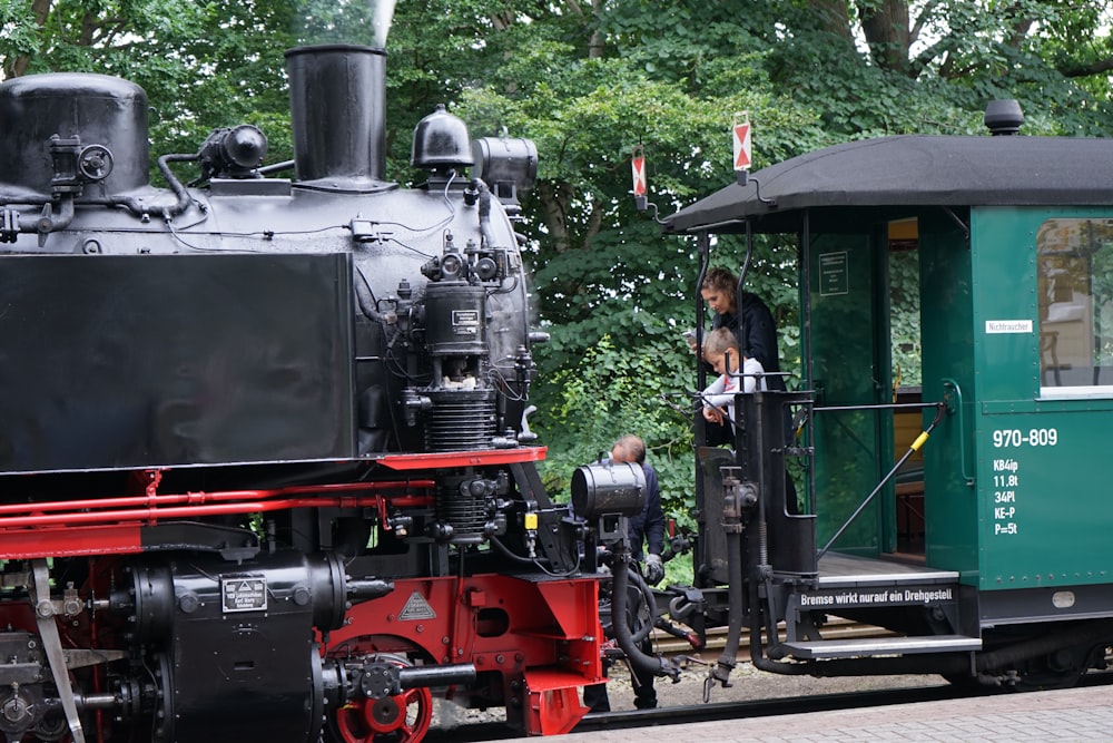 people standing beside black and red train during daytime