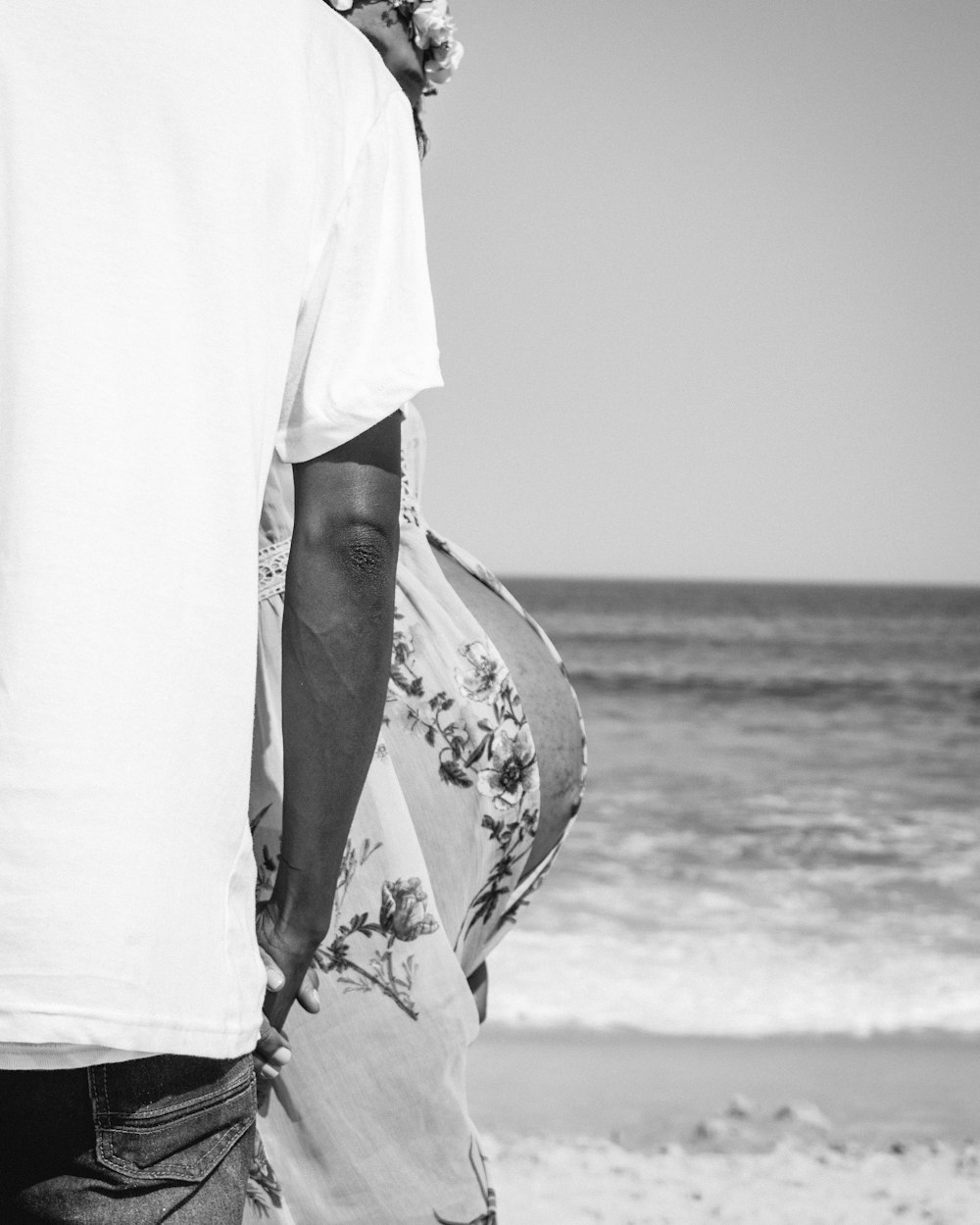 grayscale photo of person in white shirt standing on seashore