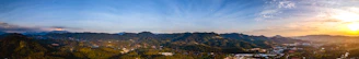 Panoramic view from the Mirador dels Àngels at sunset, showcasing lush green mountains and a vibrant sky.