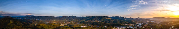 Panoramic view from the Mirador dels Àngels at sunset, showcasing lush green mountains and a vibrant sky.
