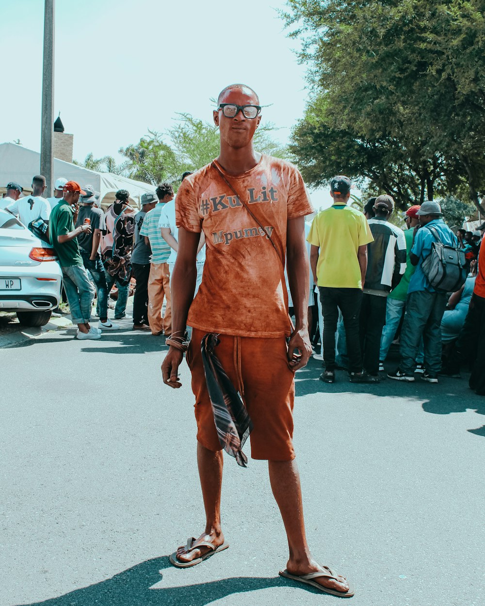 man in orange tank top and red shorts standing on road during daytime