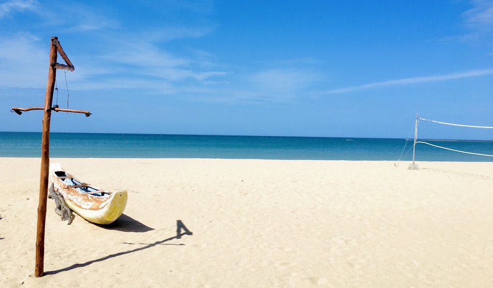 yellow and blue boat on white sand beach during daytime