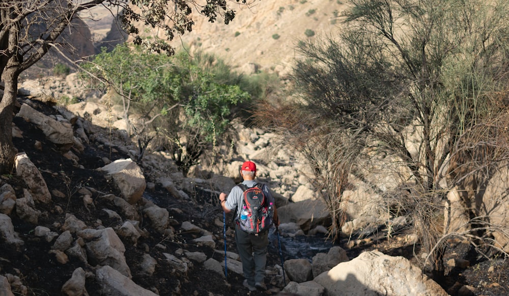 man in blue jacket and black pants walking on rocky road during daytime