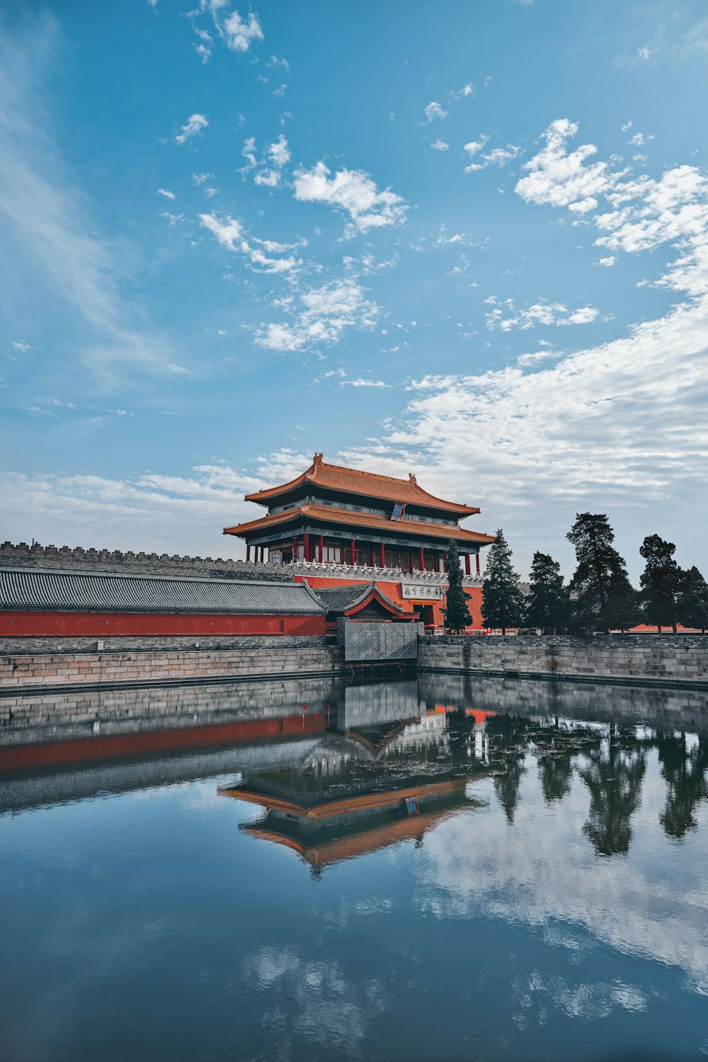 red and black temple near body of water under blue sky during daytime