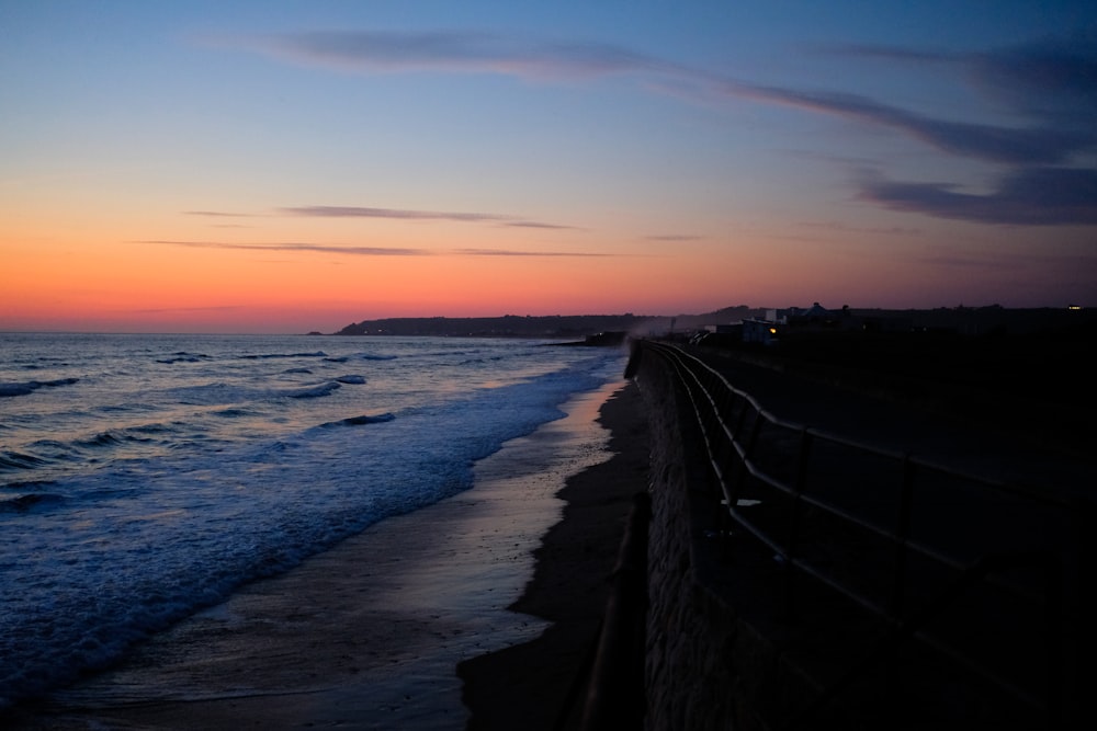 silhouette of a person walking on a beach during sunset