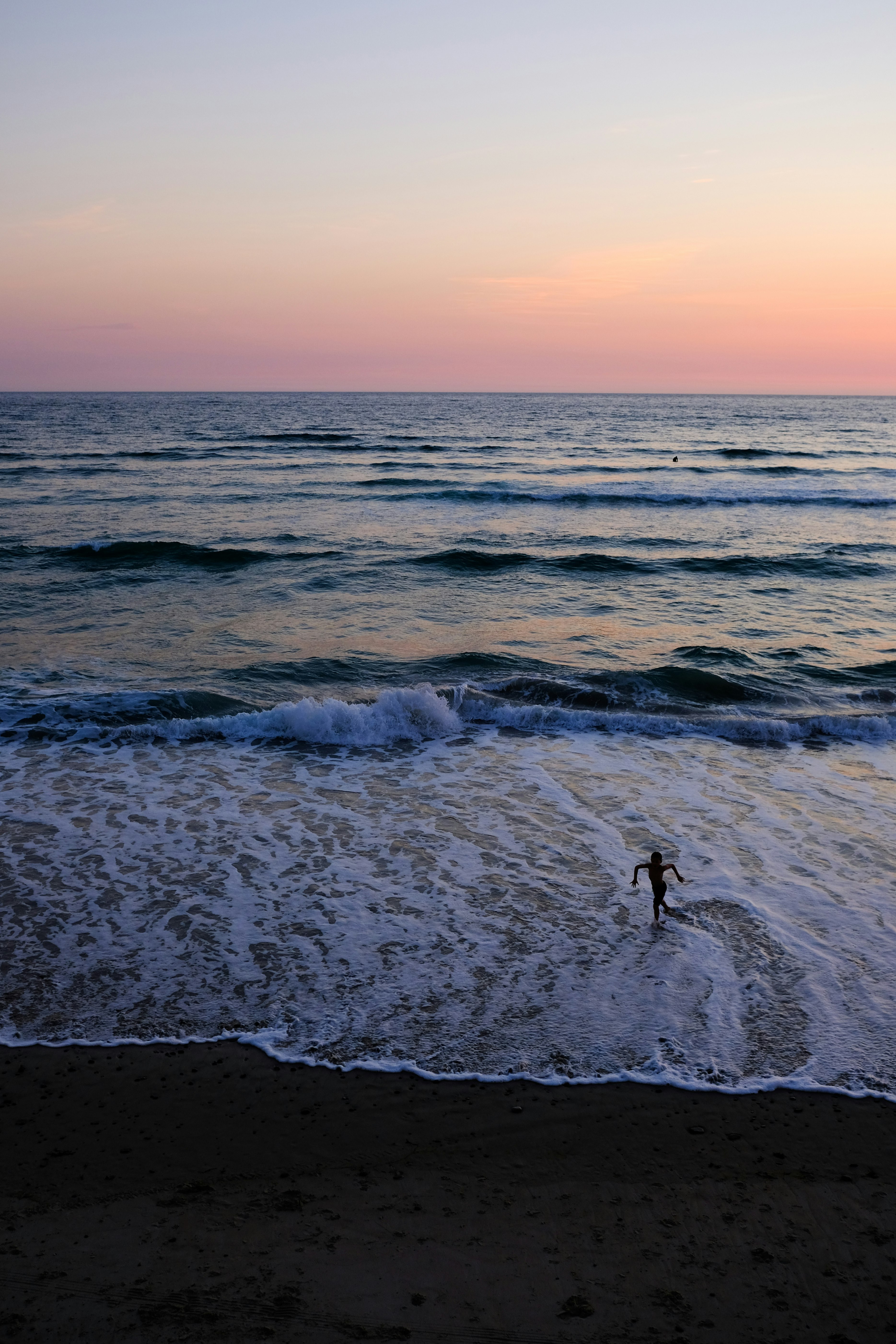 person standing on sea shore during sunset