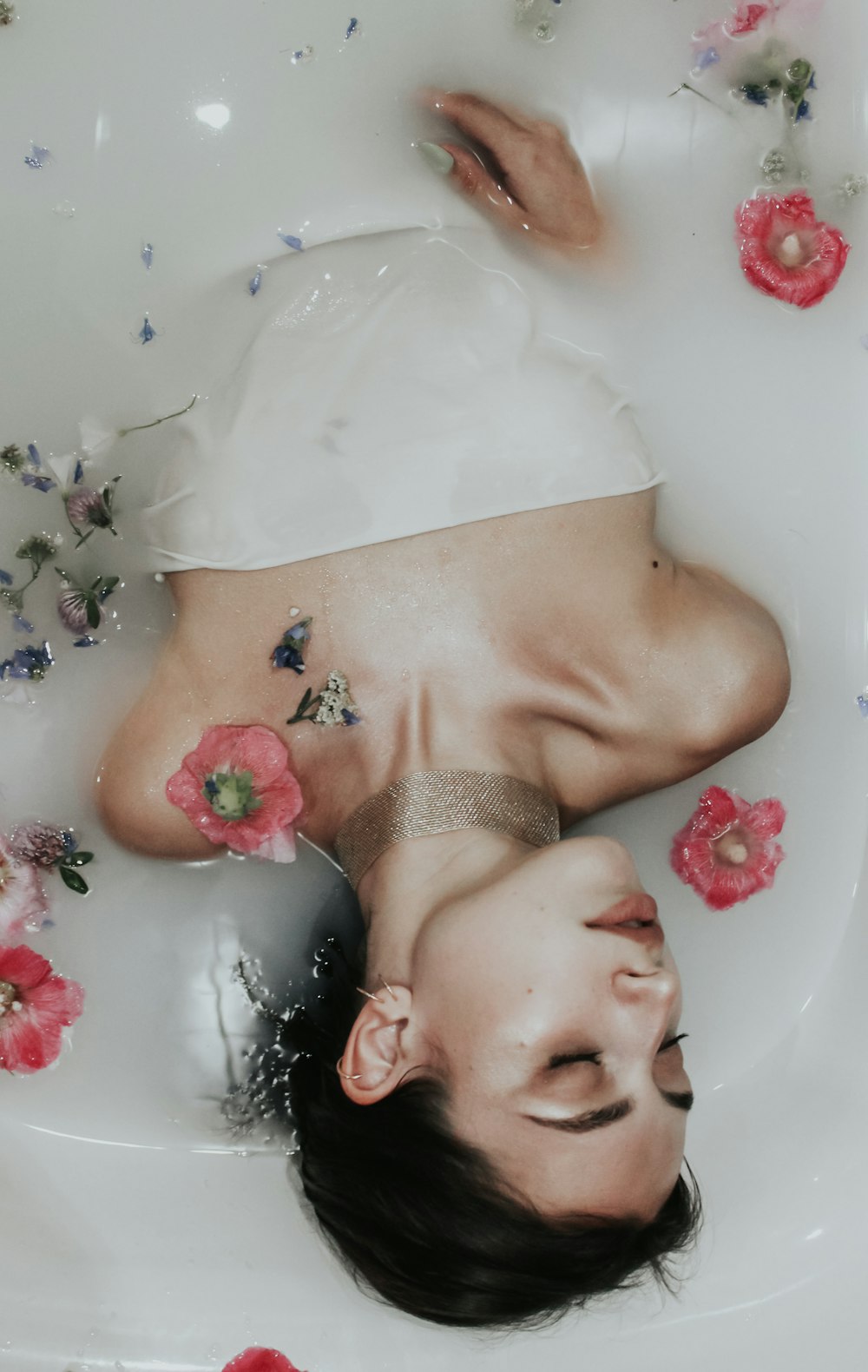 a woman laying in a bathtub with flowers all around her