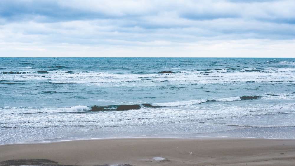 ocean waves crashing on shore during daytime