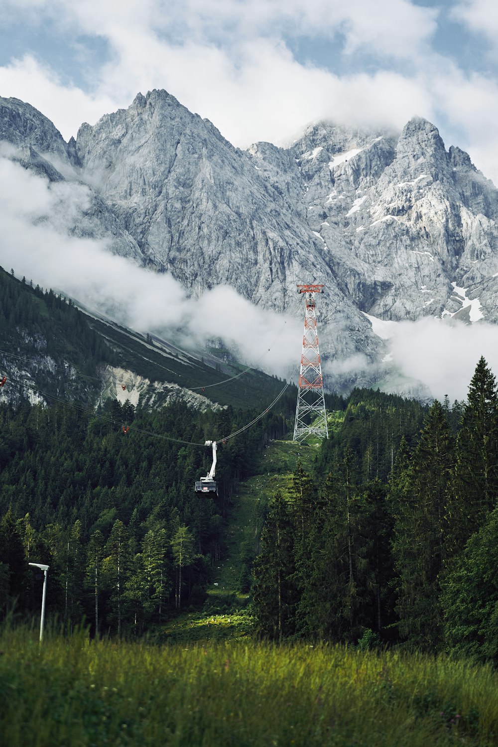 green trees near mountain under white clouds during daytime