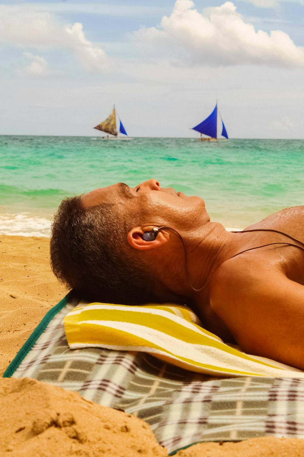 woman lying on yellow and white striped towel on beach during daytime