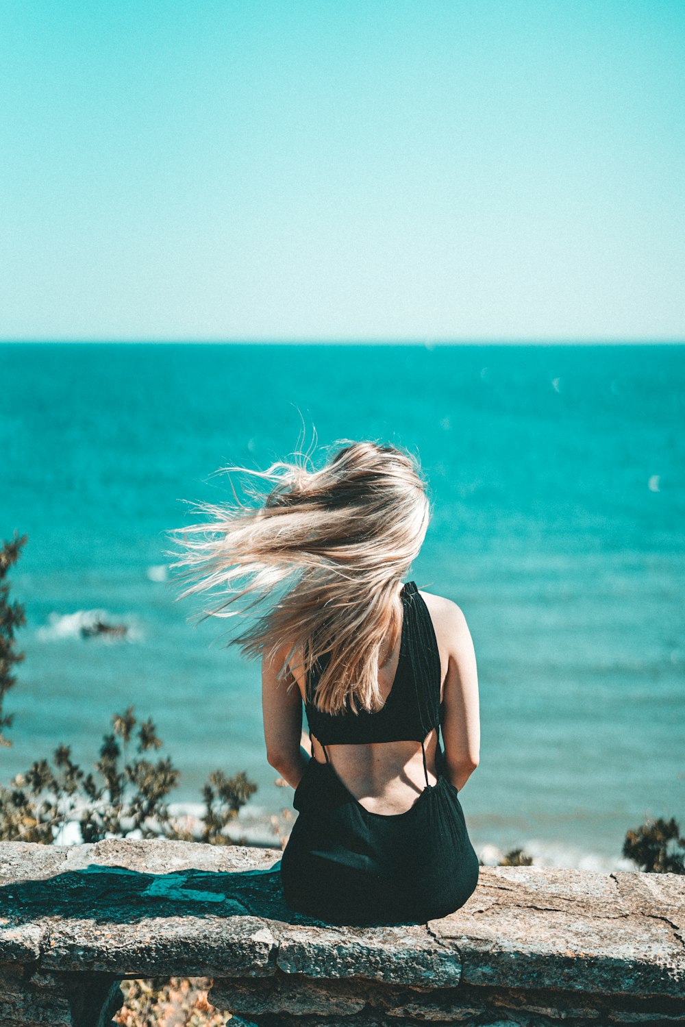donna in reggiseno nero in piedi vicino al mare durante il giorno