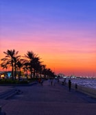 Sunset casting golden hues over the palm-lined Samaná boardwalk with visitors strolling and enjoying the view.