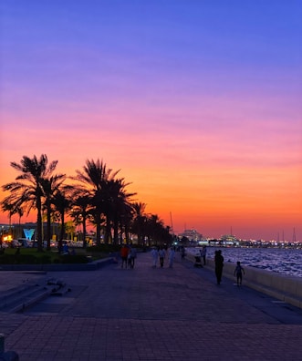 Sunset casting golden hues over the palm-lined Samaná boardwalk with visitors strolling and enjoying the view.