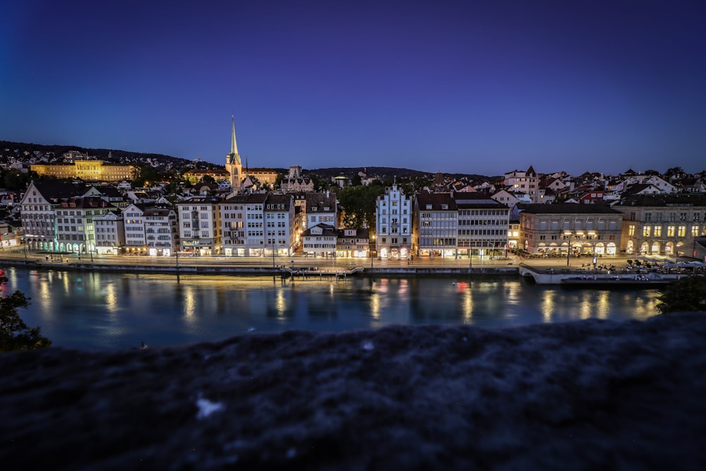 city buildings near body of water during night time