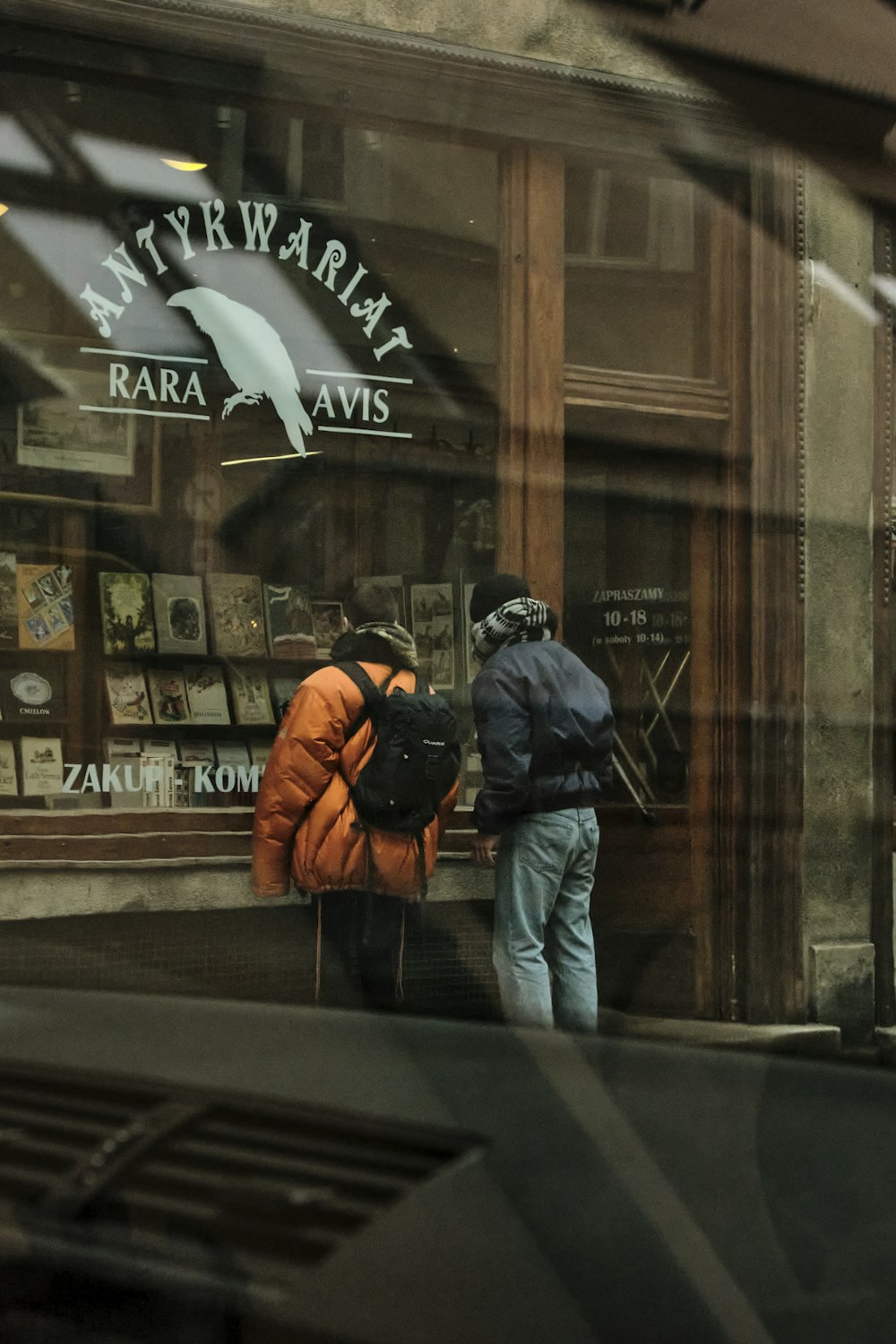 man in black jacket and blue denim jeans standing beside store