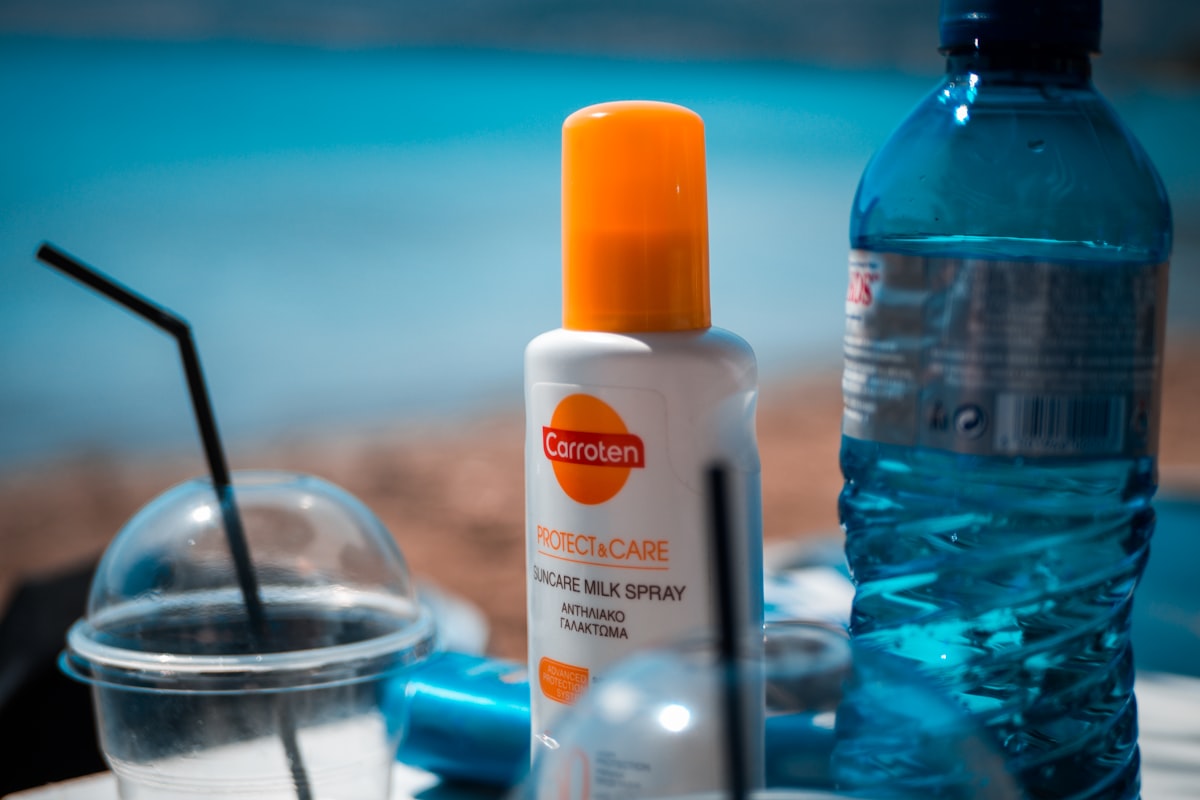 A white and orange sunscreen bottle standing on a blue table