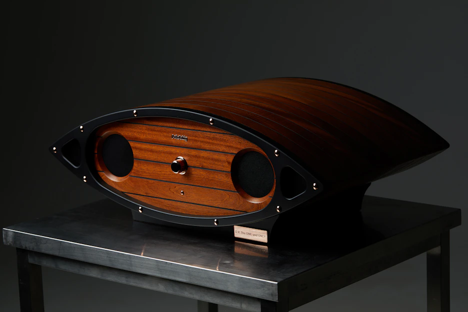 Close-up of a sleek TunerTribe Bluetooth speaker glowing softly on a wooden table