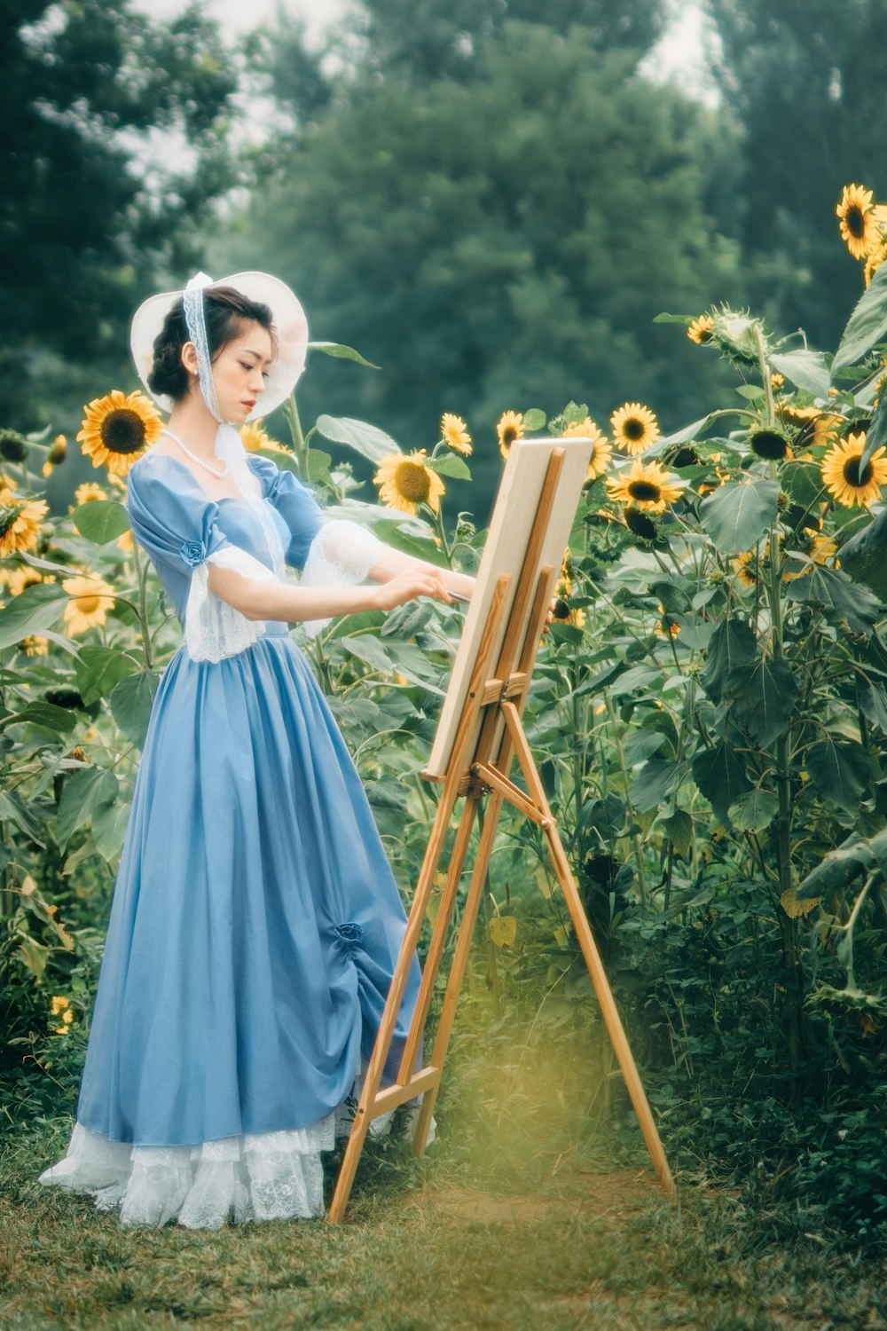 a woman in a blue dress painting a sunflower