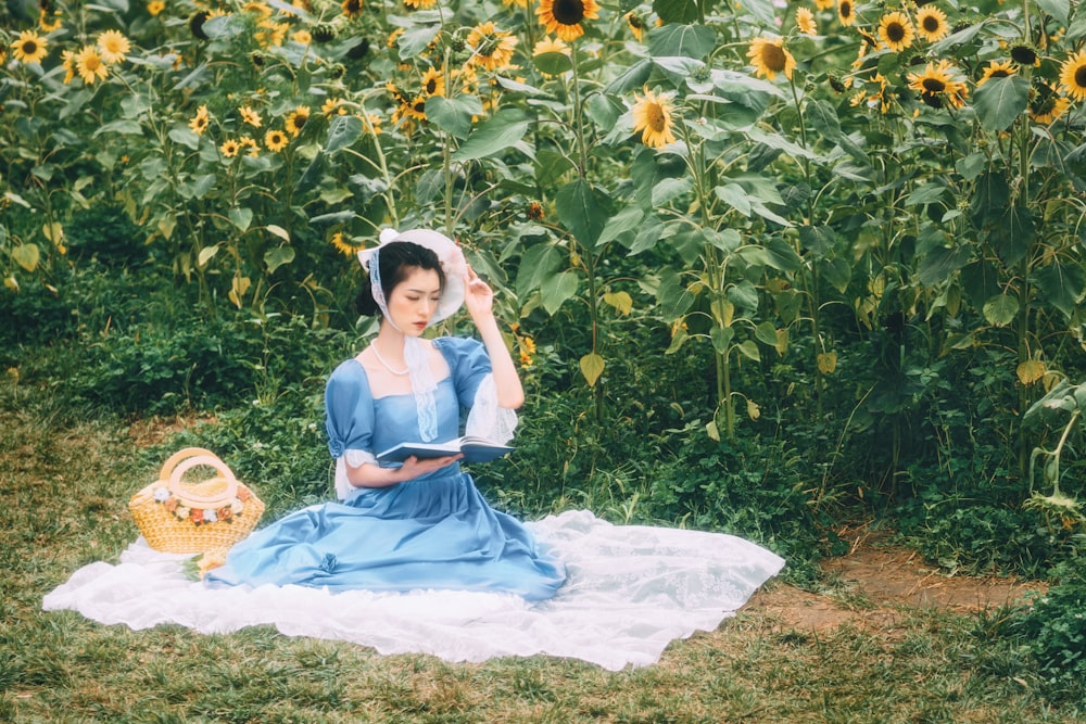 girl in blue dress sitting on white textile surrounded by green plants during daytime