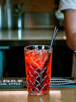 A heart horb drink in a stylish glass, with deep red hues contrasting the dark theme of the café