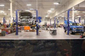 A modern auto repair workshop with mechanics working on a car engine under bright lights.