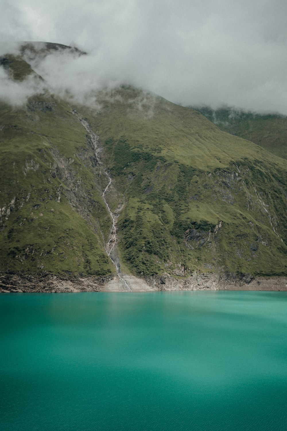 green and brown mountain beside body of water during daytime