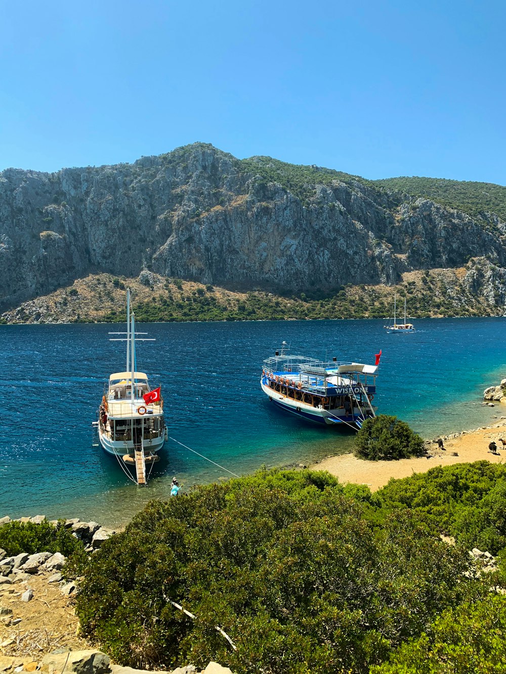 weißes und rotes Boot auf See in der Nähe der Berge tagsüber