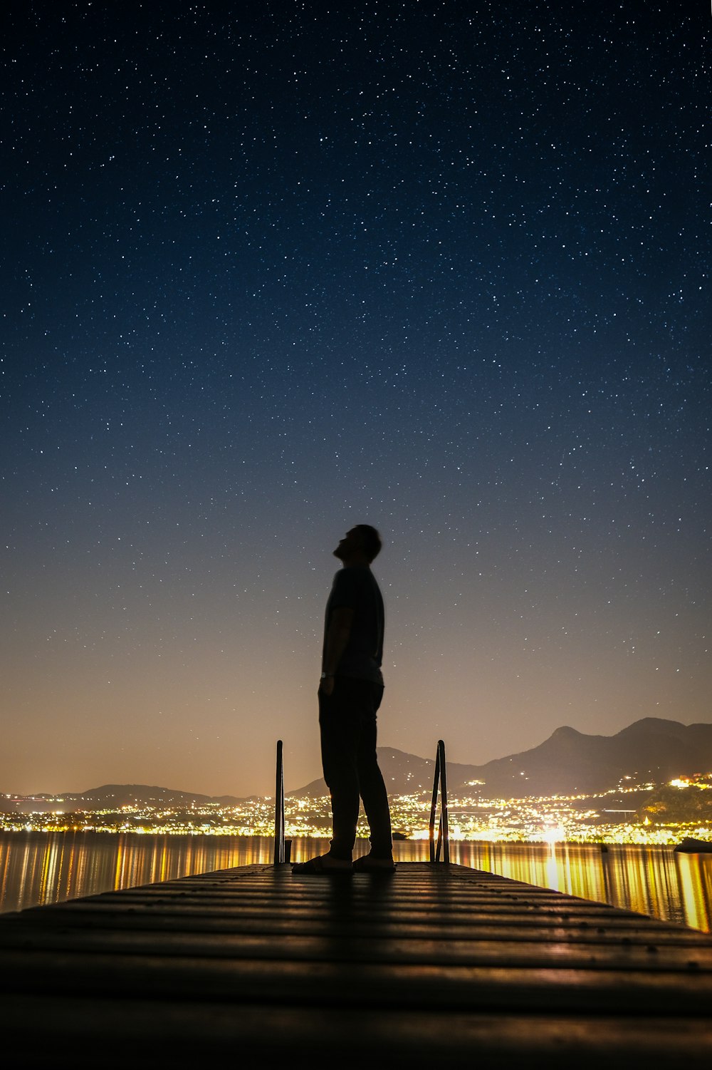 silhouette of man standing on dock during night time
