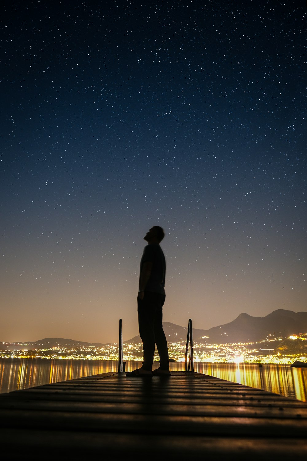 silhouette dell'uomo in piedi sul molo durante la notte