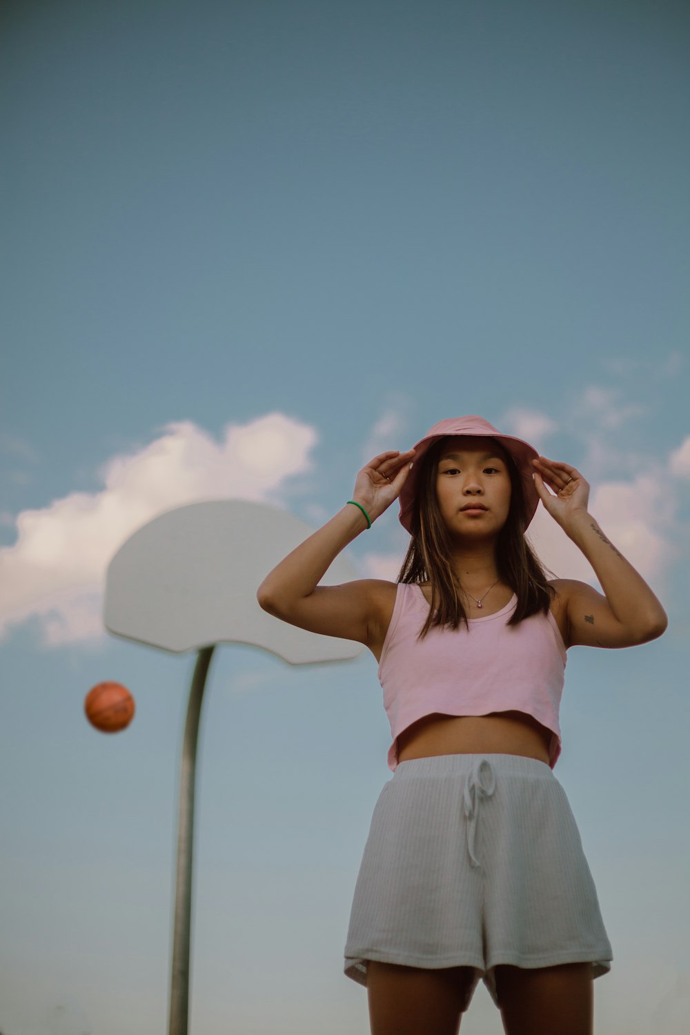 woman in white tank top and blue denim shorts holding red balloons