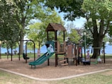 brown wooden playground surrounded by green trees during daytime