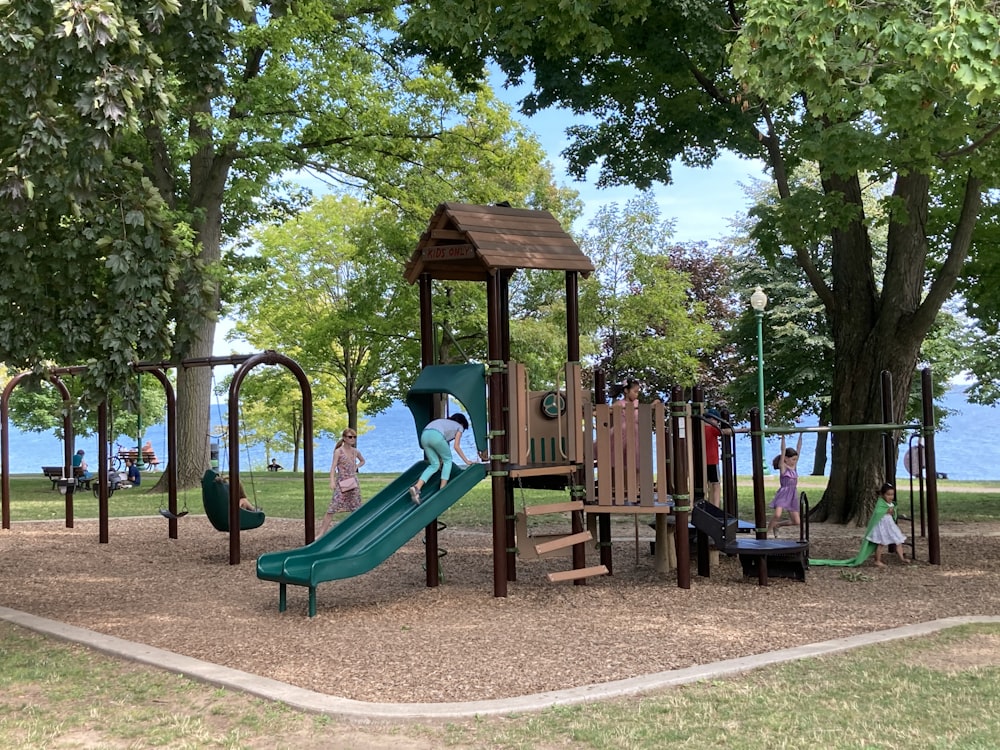 brown wooden playground surrounded by green trees during daytime