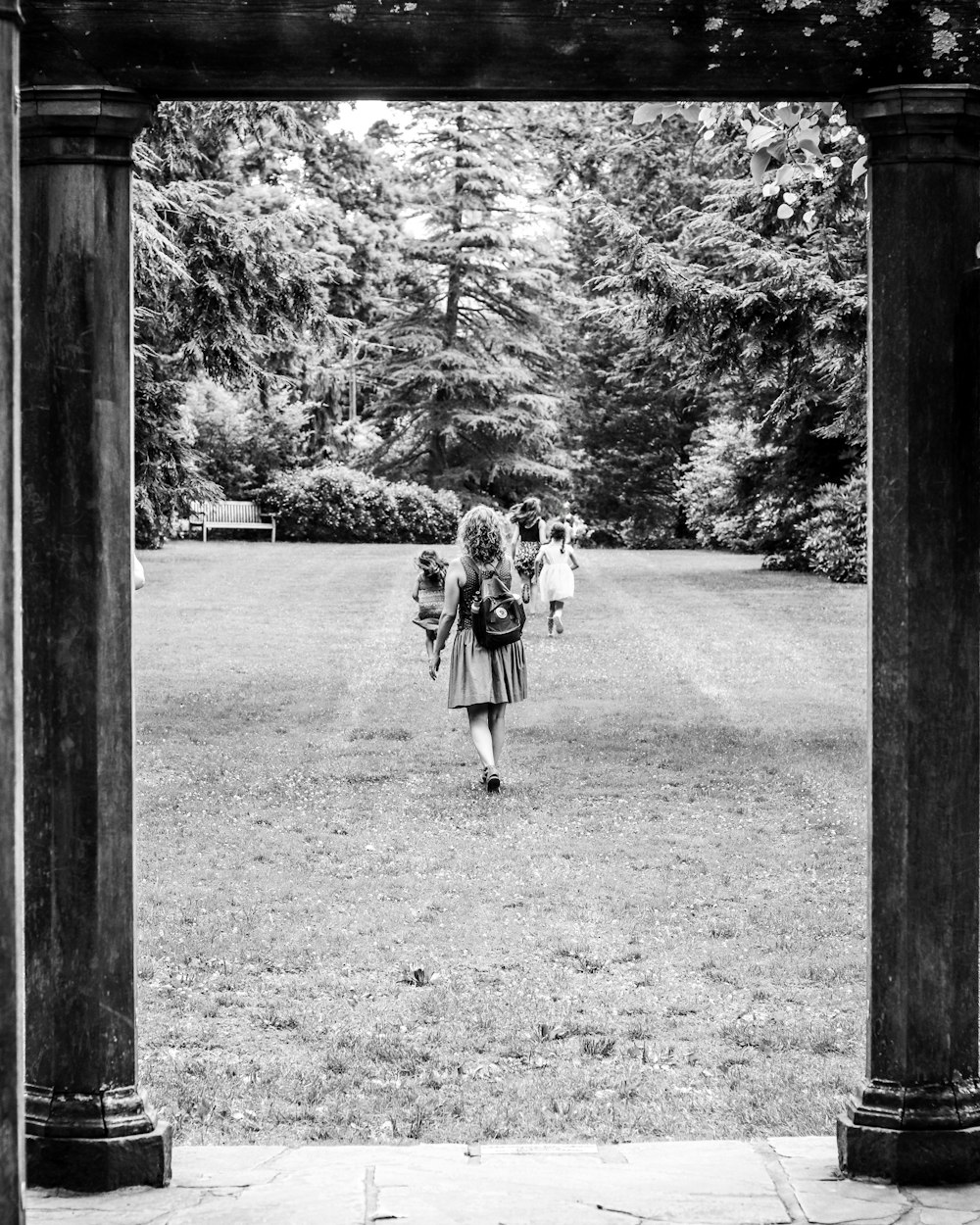 grayscale photo of 2 women standing on grass field