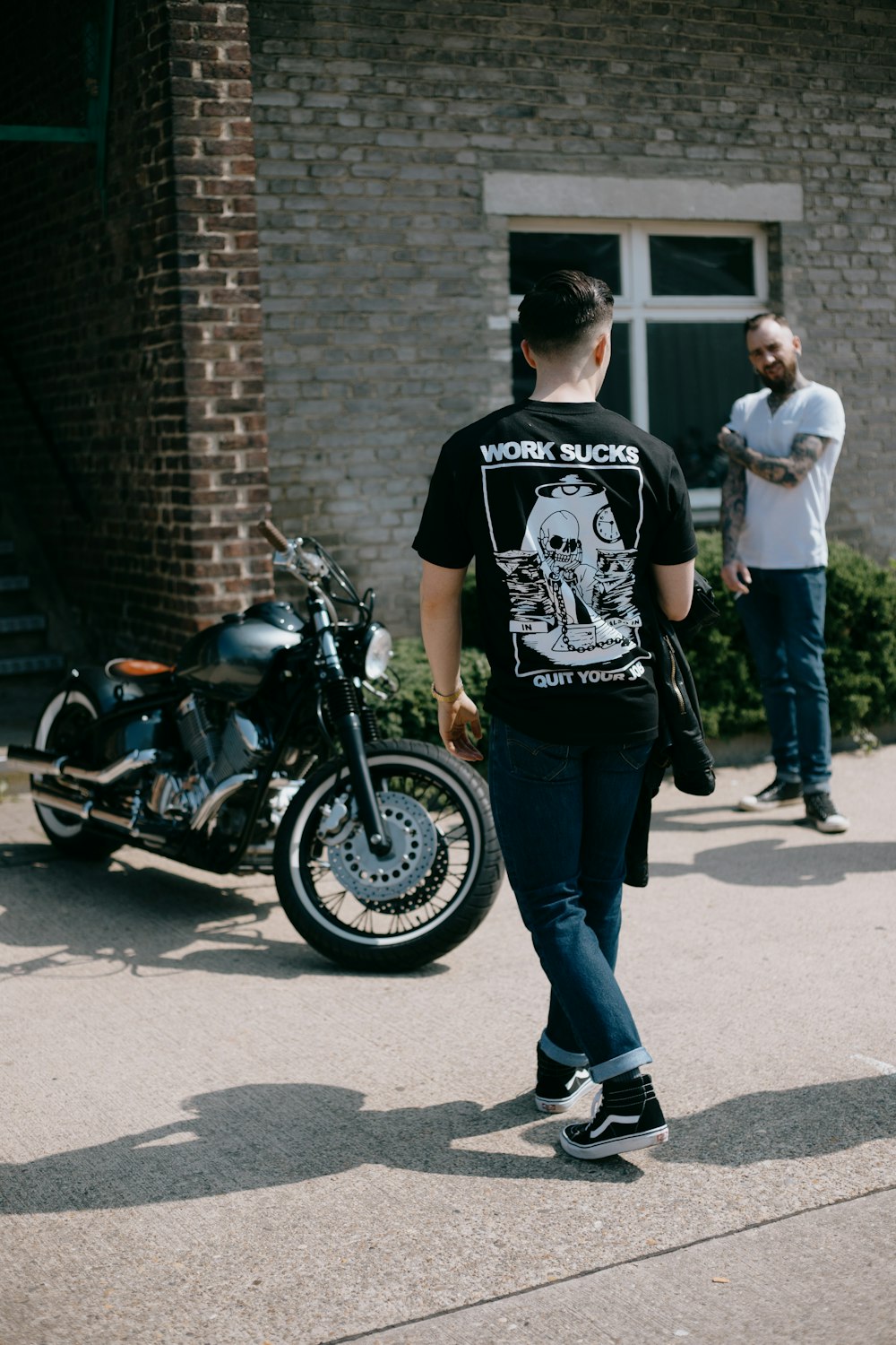 man in black and white crew neck t-shirt and blue denim jeans standing beside black