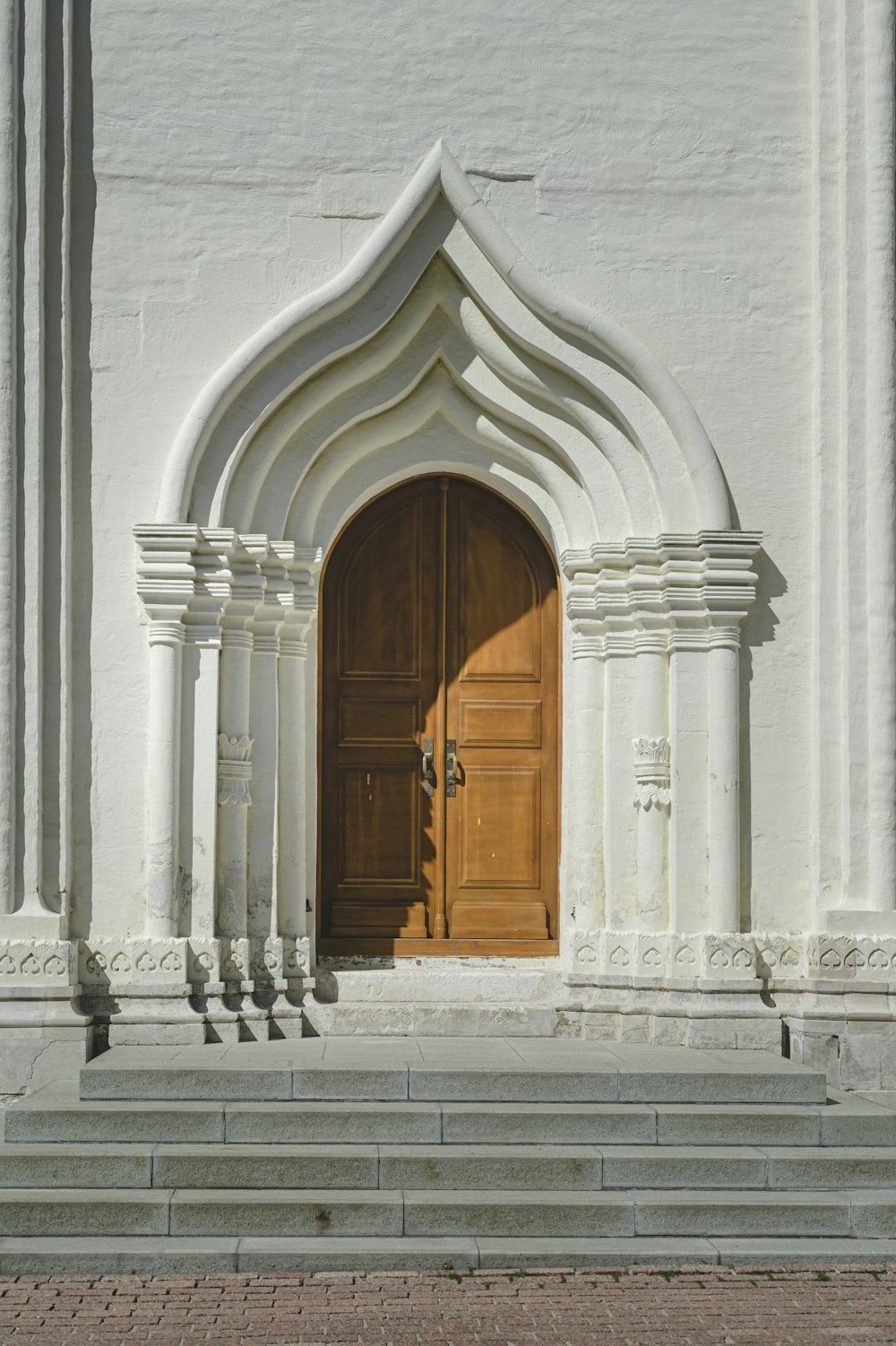 puerta de madera marrón sobre pared de hormigón blanco