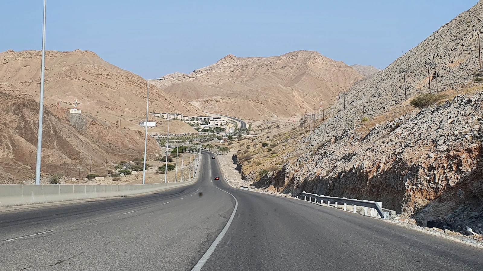 A paved road running between dry mountains near Muscat