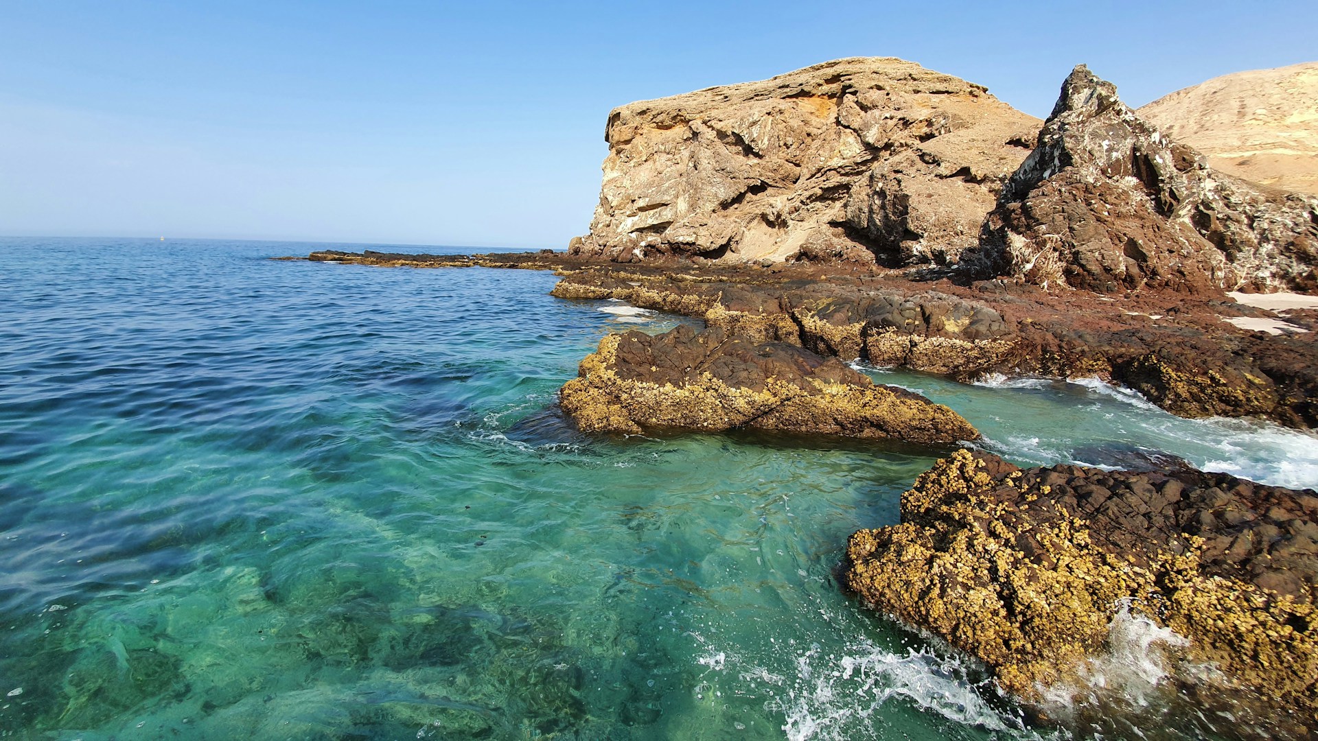 brown rock formation on body of water during daytime