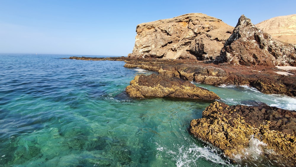 brown rock formation on body of water during daytime