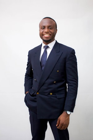 Man in a suit wearing a watch smiling against a white background