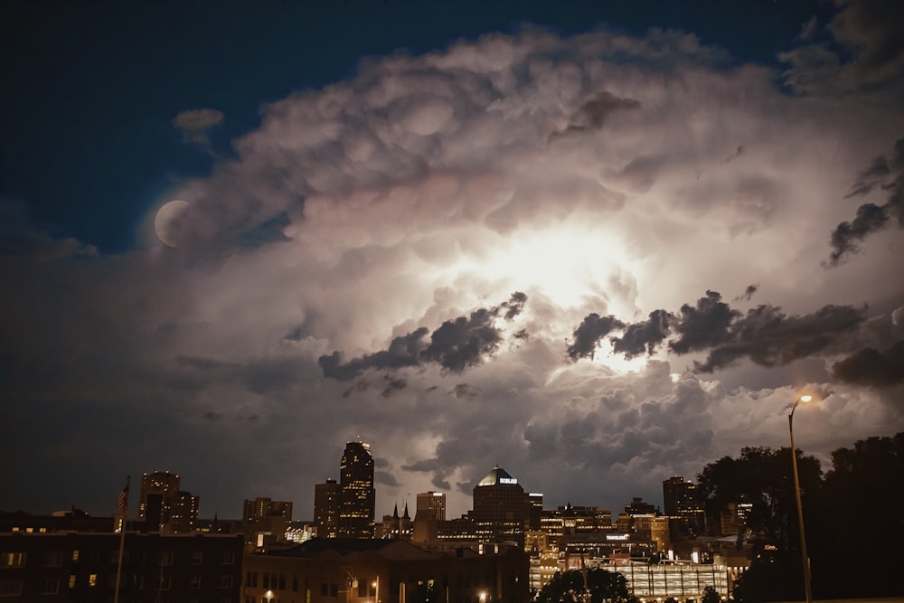 city buildings under white clouds and blue sky during night time