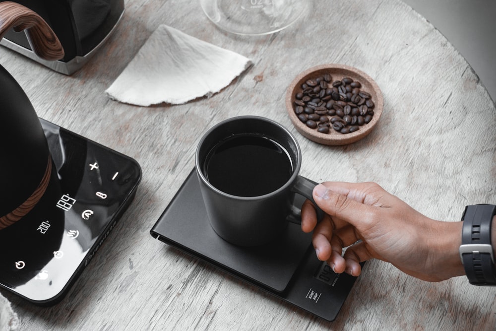 person holding black ceramic mug