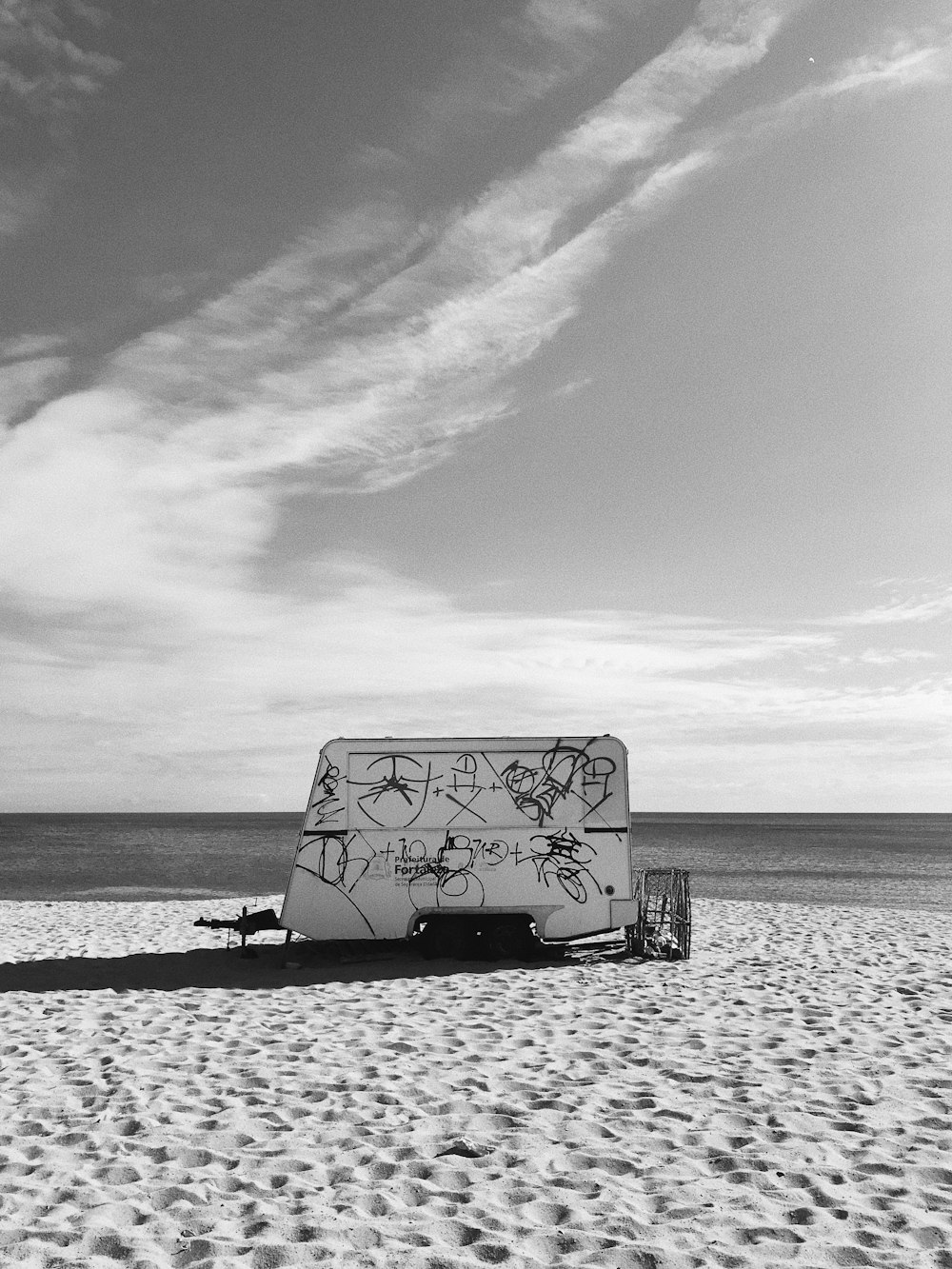 grayscale photo of person sitting on bench near sea